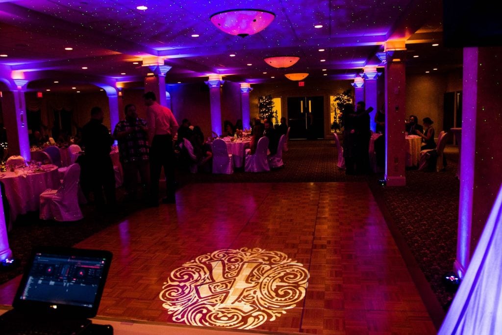 Picture of a dance floor with monogram and uplighting from a DJ table